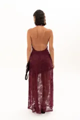 Vestido largo de encaje color bordó, con escote halter y diseño ajustado en el torso que se extiende hasta la cintura, donde continúa con una falda larga de encaje transparente.