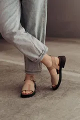 Sandalia de cuero color tostado con tiras anchas, tira en el talón y hebilla metálica rectangular ajustable. Cuenta con suela de goma con tacón bajo y plataforma.