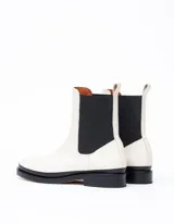 Bota Chelsea color hueso de cuero vacuno, con elástico lateral negro y suela de cuero.