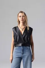 Top negro de simil cuero liviano, de escote cruzado con acceso por cierre invisible lateral. Sin mangas con espalda cerrada y frunces en hombros.