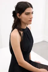 Vestido largo de encaje negro, con escote halter y falda translúcida con tajo delantero.