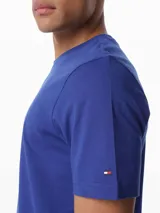 Remera de manga corta Tommy Hilfiger de cuello redondo, confeccionada en puro algodón. Presenta un diseño liso en color azul con un logo gráfico estampado en el pecho enmarcado en un recuadro blanco.