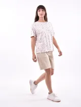 Remera de manga corta color beige con estampado de bananas en tonos amarillo, naranja y rosado.