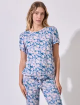 Conjunto de pijama marca Jesica Simpson, confeccionado en tejido soft con estampado floral en tonos azul y rosa. Incluye remera de manga corta con escote redondo y pantalón largo con cintura elastizada y lazo de ajuste.