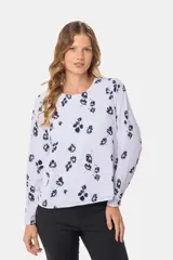 Blusa blanca con estampado de lunares negros, de manga larga y cuello redondo con abertura en la espalda.
