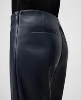 Pantalón negro de efecto cuero, corte flare o acampanado, largo hasta el tobillo. Presenta bolsillos de vivo en la espalda y cierre lateral de cremallera.