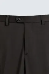 Pantalón de traje regular fit confeccionado en tejido de lana. Presenta bolsillos frontales, bolsillos traseros de vivo con botón y cierre frontal con cremallera y botón.