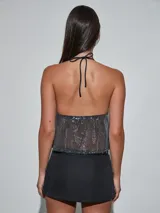 Top de lentejuelas plateadas, con escote halter y diseño fluido semitransparente.