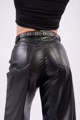 Pantalón wide-leg negro de material sintético con acabado brillante, tiro medio y bolsillos laterales. Incluye un cinturón negro con ojetes metálicos y hebilla plateada.