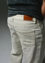 Pantalón de denim blanco de corte recto y holgado, con bolsillos laterales y pequeños detalles de etiquetas bordadas de la marca.