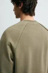 Sudadera relaxed fit color verde militar con efecto lavado, cuello redondo y manga larga. Confeccionada en tejido de algodón con interior afelpado y acabados en rib.