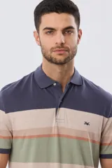 Remera polo de manga corta con diseño de franjas horizontales en tonos azul, beige, verde y terracota. Presenta cuello camisero con cierre frontal de dos botones y un pequeño bordado en el pecho.
