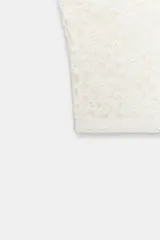 Top corto tipo bandeau de encaje blanco, sin tirantes y con borde festoneado.