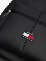 Mochila Tommy Jeans Essential Daily en color negro, confeccionada en poliuretano y poliéster. Cuenta con un compartimento principal con cierre de cremallera, un bolsillo exterior frontal con cierre y el logo bordado de la marca. Dispone de asa superior y correas ajustables acolchadas.