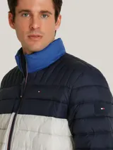 Chaqueta acolchada de diseño color block en tonos azul marino, blanco y azul brillante. Presenta cuello alto, cierre frontal con cremallera y bolsillos laterales con cierre. Incluye el logo de la marca bordado en el pecho y detalle distintivo en la manga.