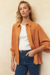 Camisa blanca de mangas abullonadas con sutiles plisados frontales, cuello clásico y corte relajado.