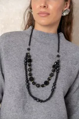 Collar de doble hilera en color negro, compuesto por una combinación de cuentas facetadas, esferas aterciopeladas y pequeños detalles metalizados dorados que aportan textura y sofisticación.