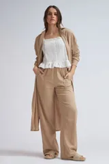 Camisa larga de lino color beige, de corte oversize, con mangas largas, cuello camisero y cierre frontal de botones. Presenta dobladillo curvo con aberturas laterales.