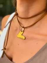 Collar tipo choker con doble tira de cuero marrón y dije en forma de corazón irregular color dorado.