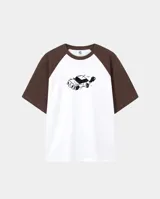 Remera de corte oversize con mangas tipo raglán en color marrón y cuerpo en color blanco. Presenta un estampado central de un auto estilo caricatura en color negro.