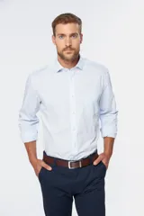 Camisa de vestir celeste claro, de corte clásico, con cuello italiano, manga larga con puños abotonados, bolsillo en el pecho y cierre frontal con botones.