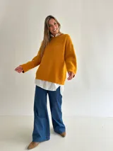 Sweater de punto con textura tipo waffle, color mostaza, de corte holgado, cuello redondo y mangas largas con puños acanalados.