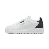Championes urbanos Puma modelo Shuffle Downtown, de diseño clásico con base blanca y detalle en azul marino en el talón. Presenta el logo de la marca en dorado en el lateral y la lengüeta, con suela de goma blanca y cordones al tono.