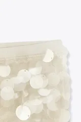 Minifalda color blanco cubierta de lentejuelas, con cintura elástica y forro interior.