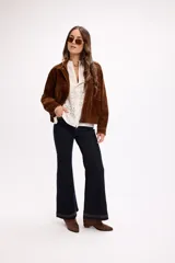 Cárdigan de tejido calado color blanco, con cierre frontal completo, cuello alto y mangas largas. Presenta un diseño con patrón de perforaciones geométricas y ajuste relajado.