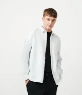 Camisa celeste de algodón, corte oversized, manga larga, cuello camisero, dos bolsillos frontales con solapa y cierre con botones.