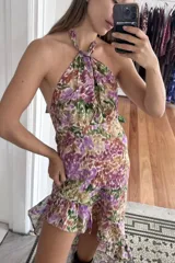 Vestido midi con diseño asimétrico y volados en el ruedo. Presenta escote halter con tiras ajustables al cuello y espalda descubierta.