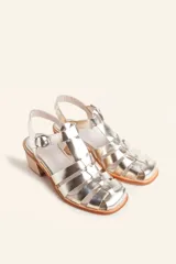 Sandalia plateada de cuero con tiras entrecruzadas, taco de madera y hebilla lateral.