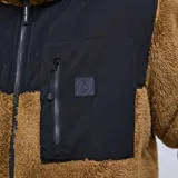 Campera de polar tipo sherpa color marrón, con paneles de tela técnica negra en el pecho y bolsillos con cierre. Presenta cuello alto y cierre frontal completo.