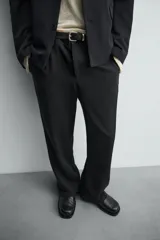 Pantalón de corte relaxed fit confeccionado en tejido con mezcla de lana, con bolsillos delanteros y traseros de vivo, cierre frontal con cremallera y botón.