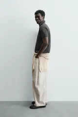 Jersey de punto color verde oliva, de calce relajado (relaxed fit), con cuello solapa y abertura frontal en forma de V. Es de manga corta y presenta acabados en rib en puños y ruedo.