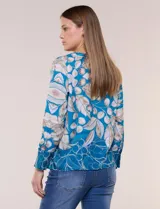 Blusa de silueta holgada y corte recto con caída fluida, escote redondo y mangas largas con puños anchos estructurados, con estampado floral en tonos pasteles sobre fondo blanco.