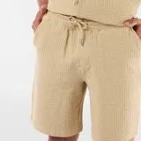 Bermuda de punto grueso color beige, de diseño liso, con bolsillos laterales y cintura elástica.