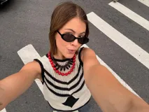 Chaleco calado negro con diseño de rayas diagonales rojas, beige y blancas.