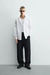 Camisa de corte slim fit confeccionada en tejido de algodón con textura. Presenta cuello italiano, manga larga con puños abotonados y cierre frontal mediante botonadura.