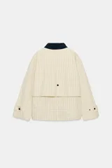 Chaqueta de corte recto confeccionada en algodón con estampado de cuadros. Presenta cuello solapa en color azul marino a contraste, cierre frontal con botones ocultos bajo solapa, bolsillos laterales y mangas largas con trabillas ajustables en los puños.