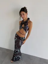 Top halter con estampado abstracto en tonos marrones y celestes, con abertura circular en el centro del pecho y lazos finos para atar en el cuello y la espalda.