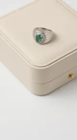 Anillo de plata 925 con diseño robusto, presenta una piedra central ovalada de esmeralda rodeada por un halo de circonias brillantes.