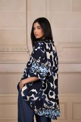 Camisa de manga corta con estampado abstracto en tonos azul marino, azul claro y blanco, y un patrón floral en el dobladillo.