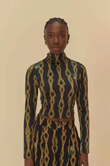 Top negro con estampado de cadenas doradas, cuello alto y mangas largas.