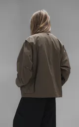 Campera técnica liviana color beige, confeccionada en microfibra de alta densidad con acabado mate. Presenta mangas desmontables que permiten convertirla en chaleco, cuello tipo camisa, cierre frontal oculto bajo cartera y logo bordado en el pecho. Incluye cuatro bolsillos frontales de gran tamaño con solapa y puños con elástico.