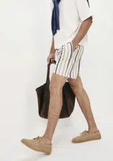 Short de tela con estampado a rayas verticales en tonos blanco, rojo y azul. Tiene cintura elástica con cordón ajustable y bolsillos laterales.