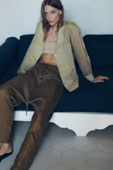 Pantalón tipo baggy de tiro bajo, confeccionado en mezcla de lino. Presenta cintura elástica con cordón ajustable, cierre frontal con botones y falsos bolsillos de vivo en los laterales.