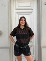 Remerón negro de encaje con mangas cortas, cuello redondo y corte holgado. Incluye un cinturón con apliques metálicos.