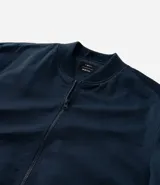 Campera tipo bomber de color beige, con cierre frontal por cremallera, cuello redondo y puños con elástico. Presenta bolsillos laterales y forro interior.