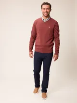 Sweater de punto con cuello en V, manga larga y puños acanalados. Presenta un pequeño logo bordado en el pecho.